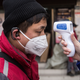 A community worker checks the temperature of courier in an Express station on January 29, 2020 in Hubei Province, Wuhan, China.